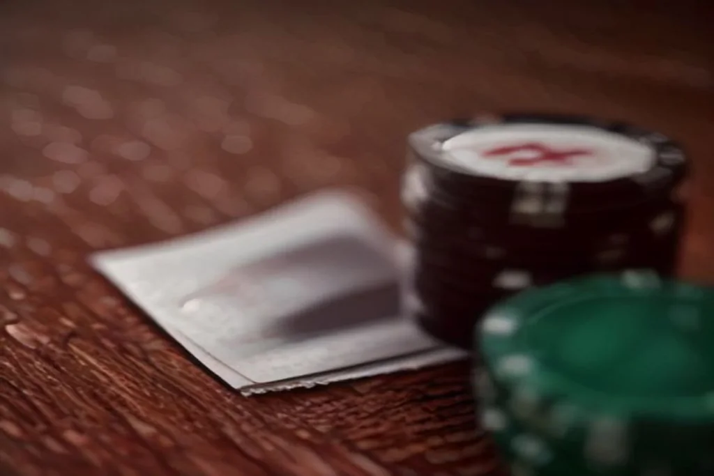 Yeşil çuha üzerinde kum saati ve poker fişleri, sakin ışık